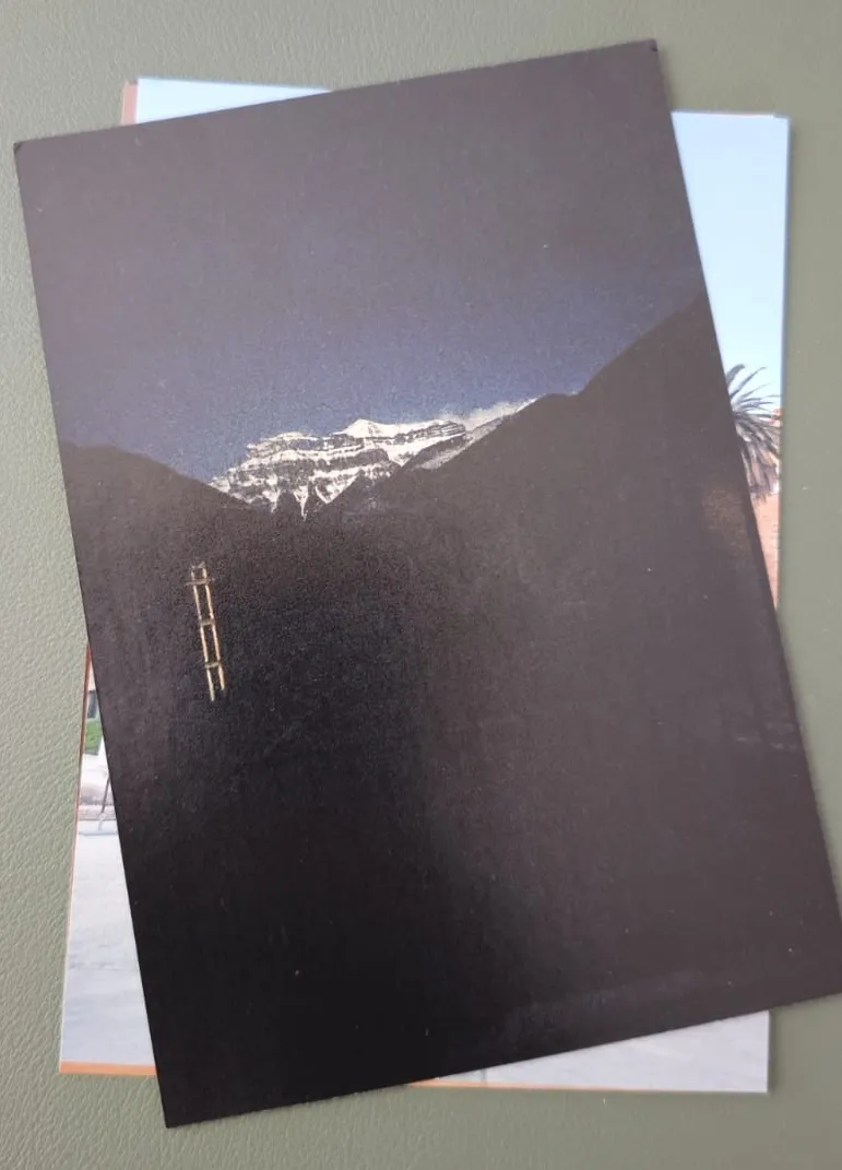 A stack of printed travel photographs including a snowy landscape.